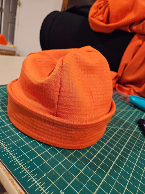 Skully Beanie - All Styles in vibrant orange fabric, perfect for outdoor adventures and cold-weather comfort.